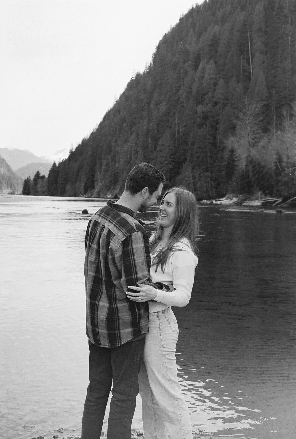 Romantic moment captured by mountain lake with evergreen forest backdrop.