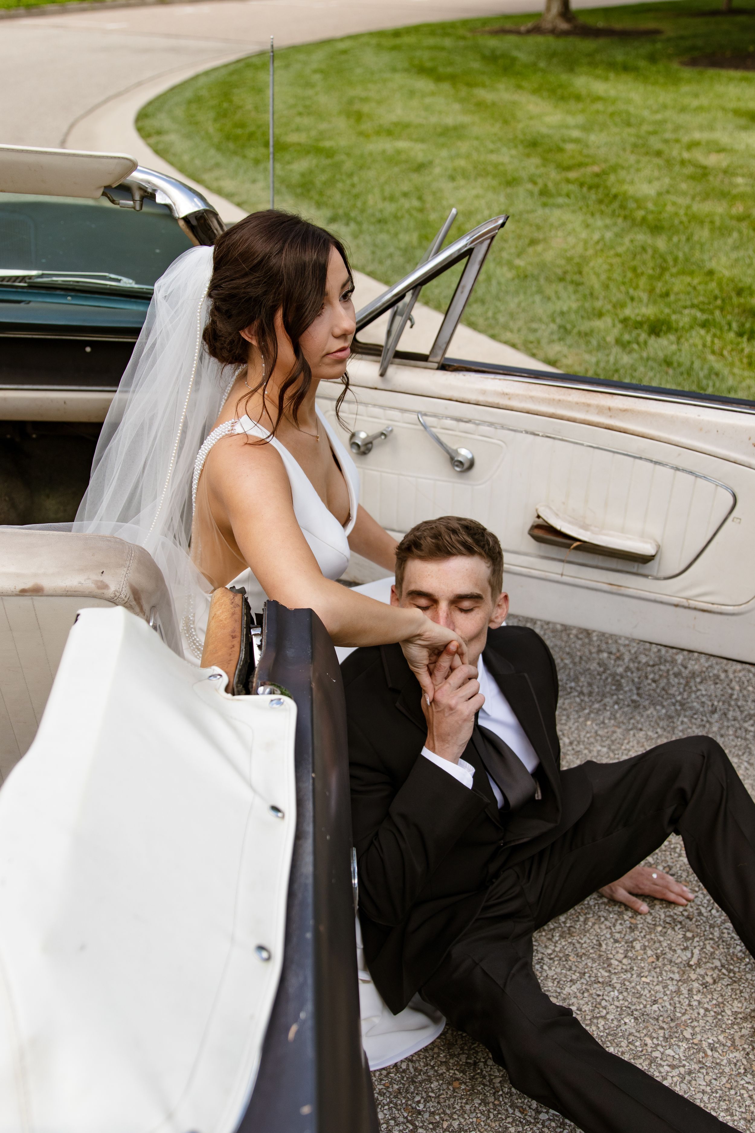 Couple enjoys champagne together in a vintage car on their wedding day.