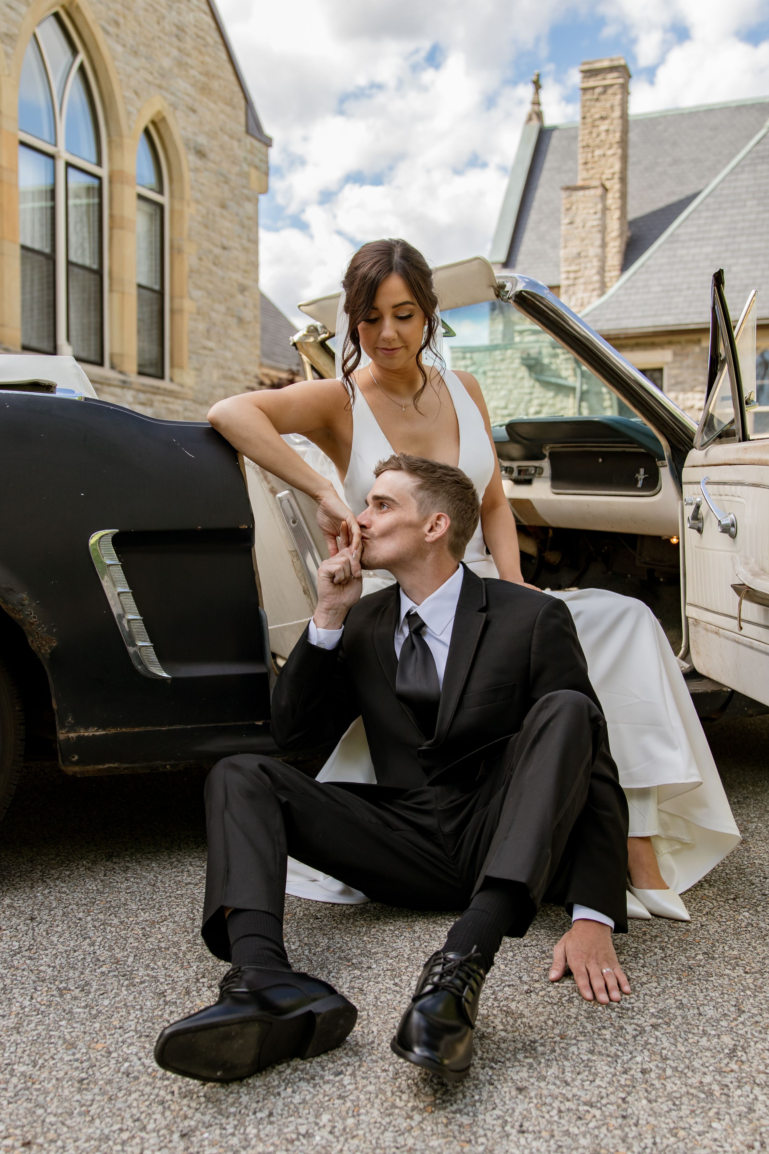 Artistic wedding photo of couple posing by classic car.
