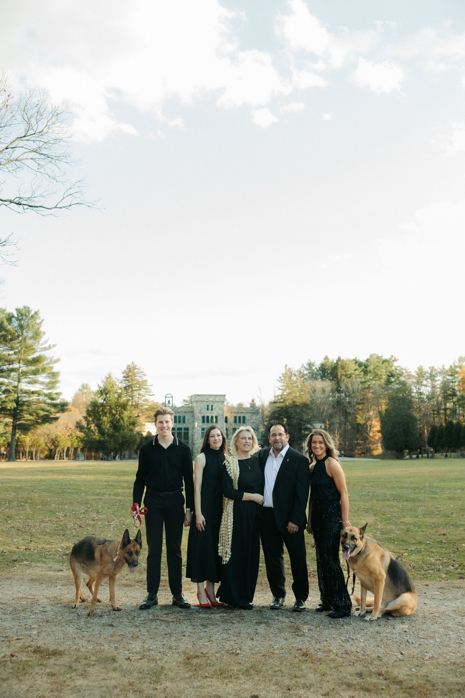 A family portrait with two German Shepherd dogs on an autumn estate lawn.