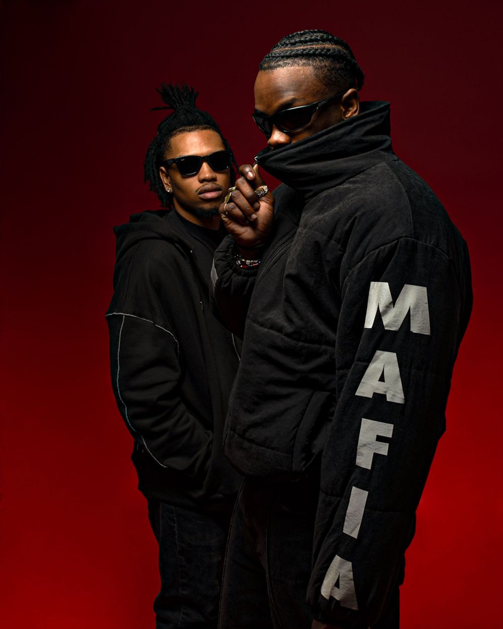 Two people in black hoodies and sunglasses pose against a dark red background, with one wearing a jacket with 'MAFIA' text.