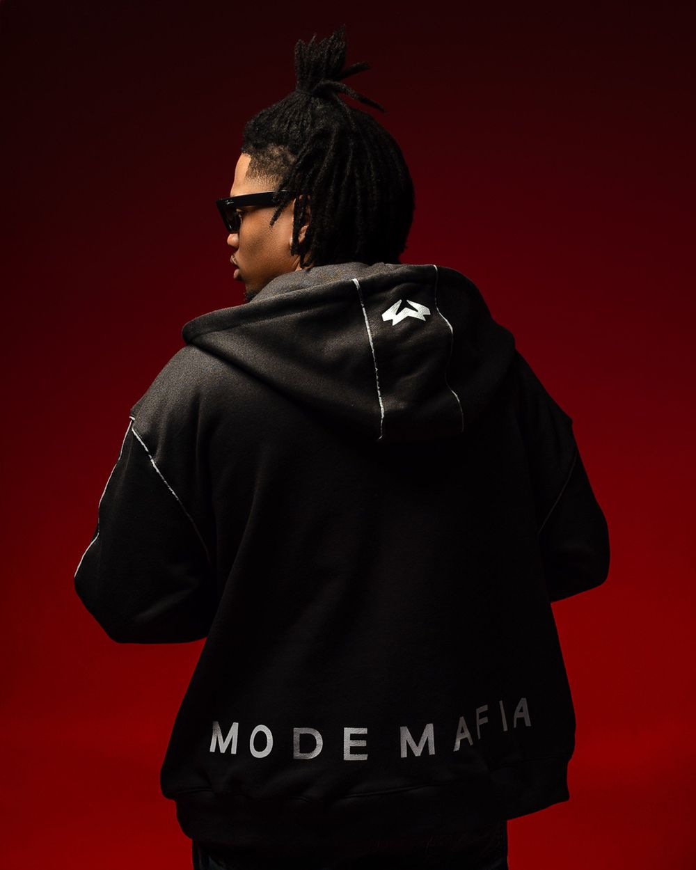 Back view of a black hoodie with 'MODE MAFIA' text against a dark red background.