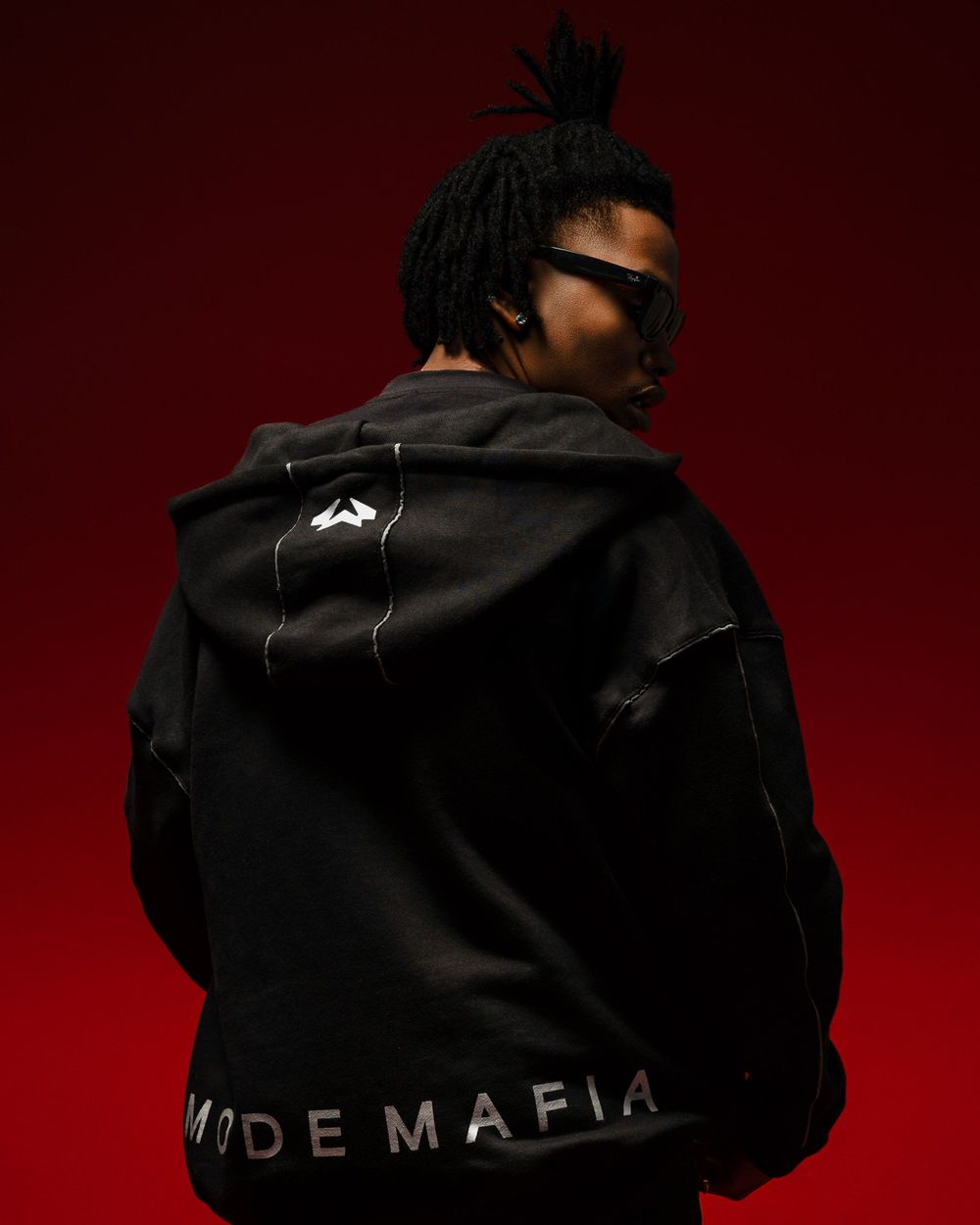 Stylish black sweatshirt with 'MODE MAFIA' branding photographed against a deep red gradient backdrop.
