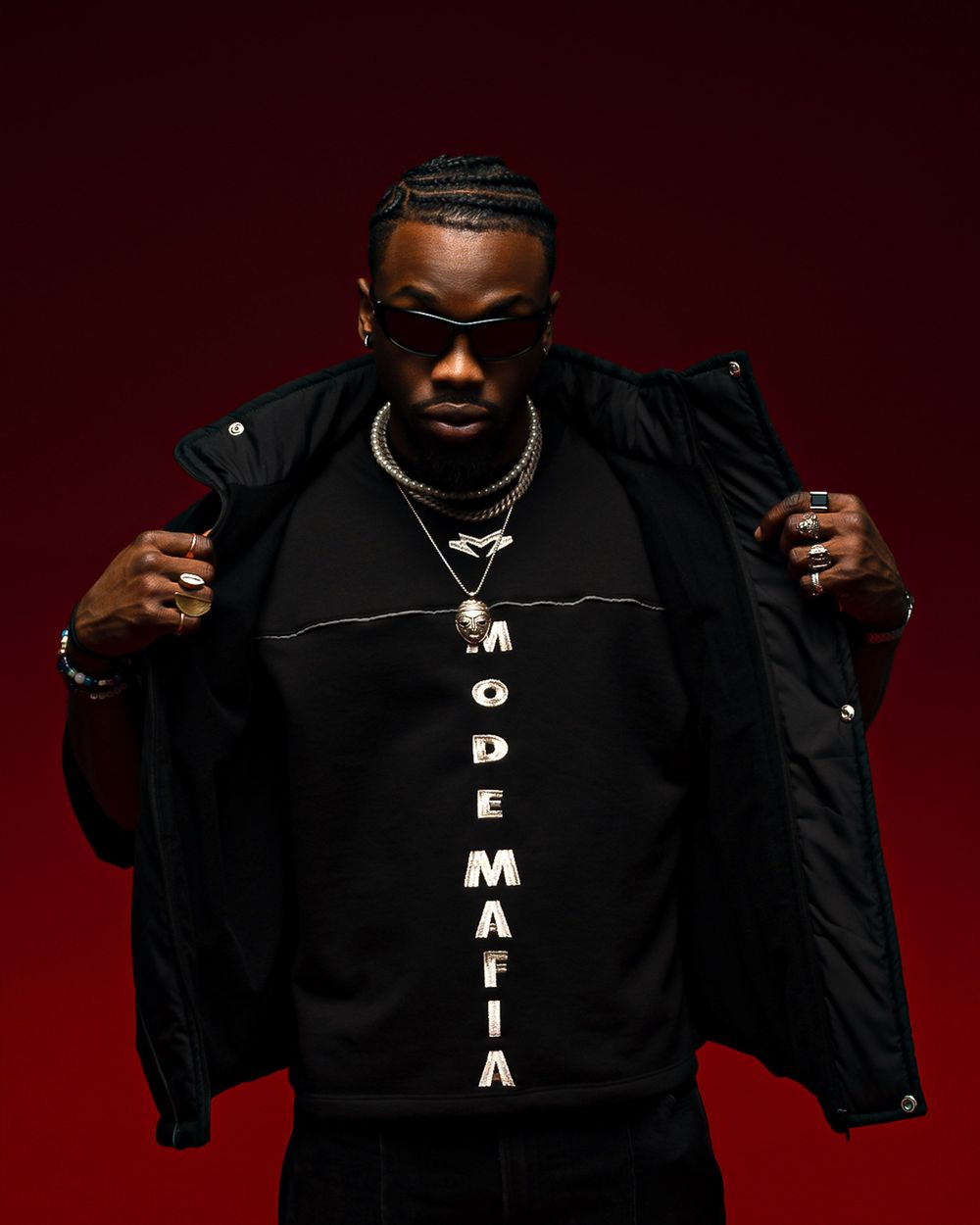 Stylish streetwear fashion photo showing black jacket with MODE MAFIA text against dark red background.