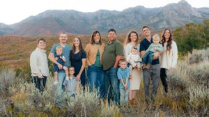 Large family posing outdoors in a mountain landscape with autumn foliage and sagebrush in background. Megan Snell Photo Utah Weddings