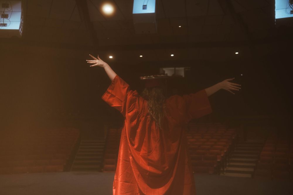 A dark theater hallway with red lighting and mysterious figures in robes creating an eerie atmosphere.