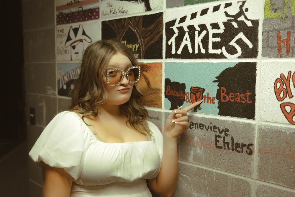 Theater hallway decorated with various show posters and artwork on the walls.