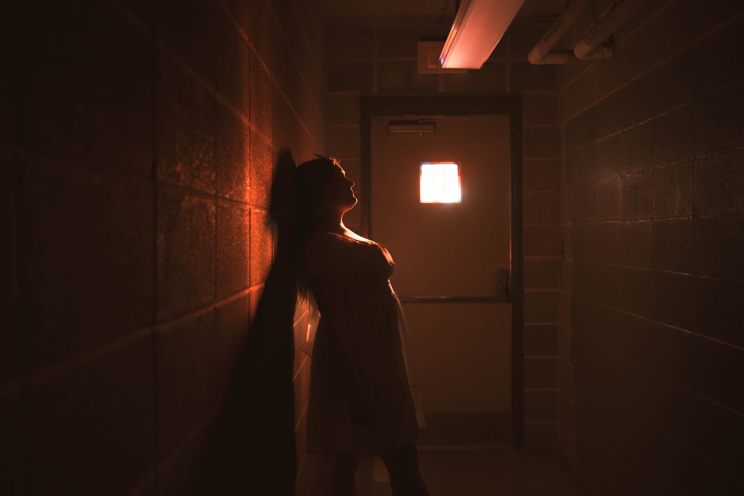 Moody corridor scene with dramatic red lighting and shadowy figures.
