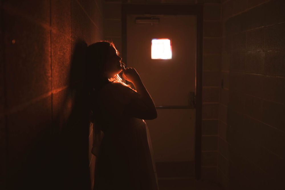 Silhouetted figures in a dark hallway with dramatic red lighting.