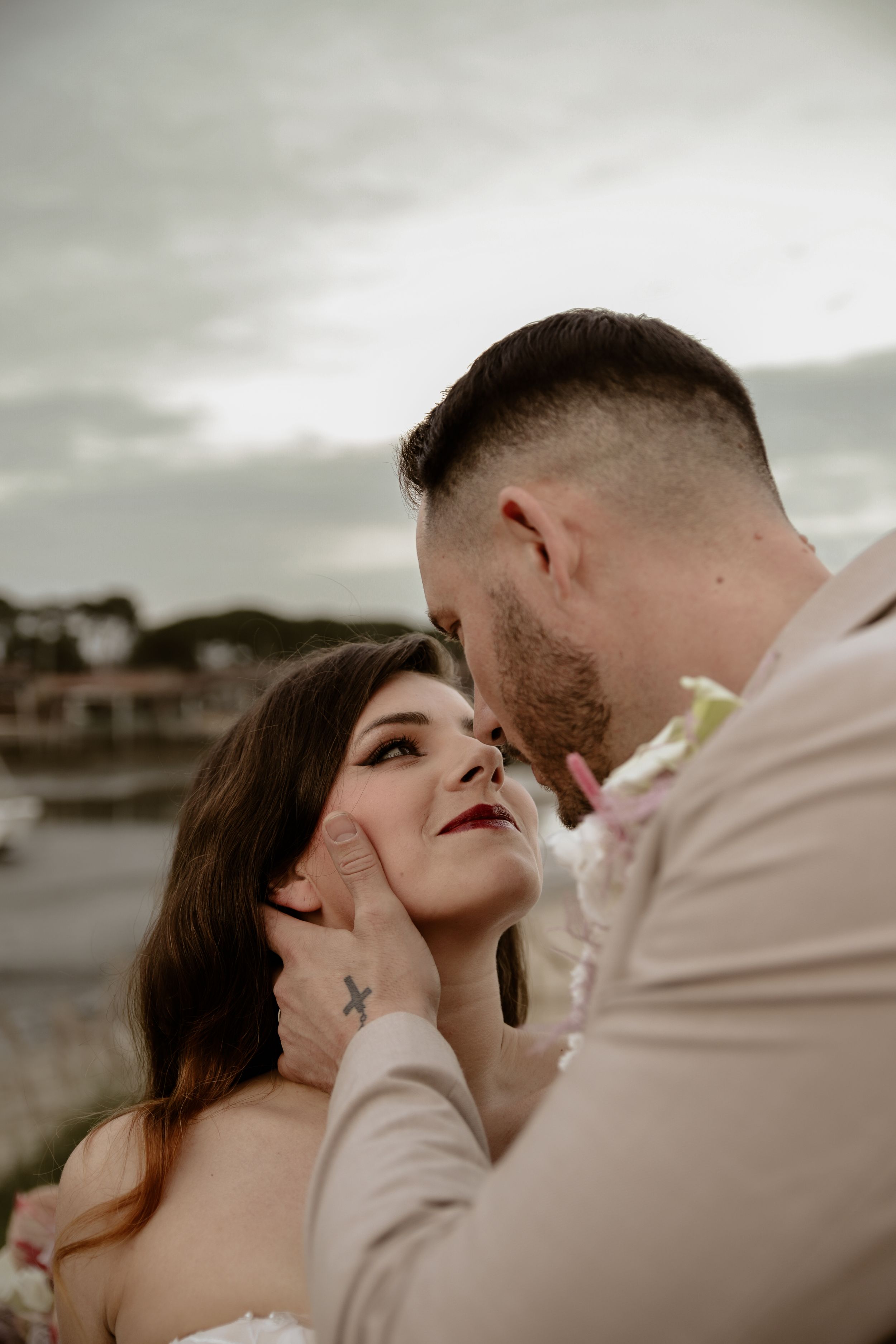 Intimate close-up of newlyweds sharing tender moment by seaside.