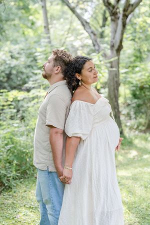 Couple dos à dos lors d'une séance photo de grossesse au bord du fleuve à Saint-Augustin-de-Desmaures par Judith Trudel