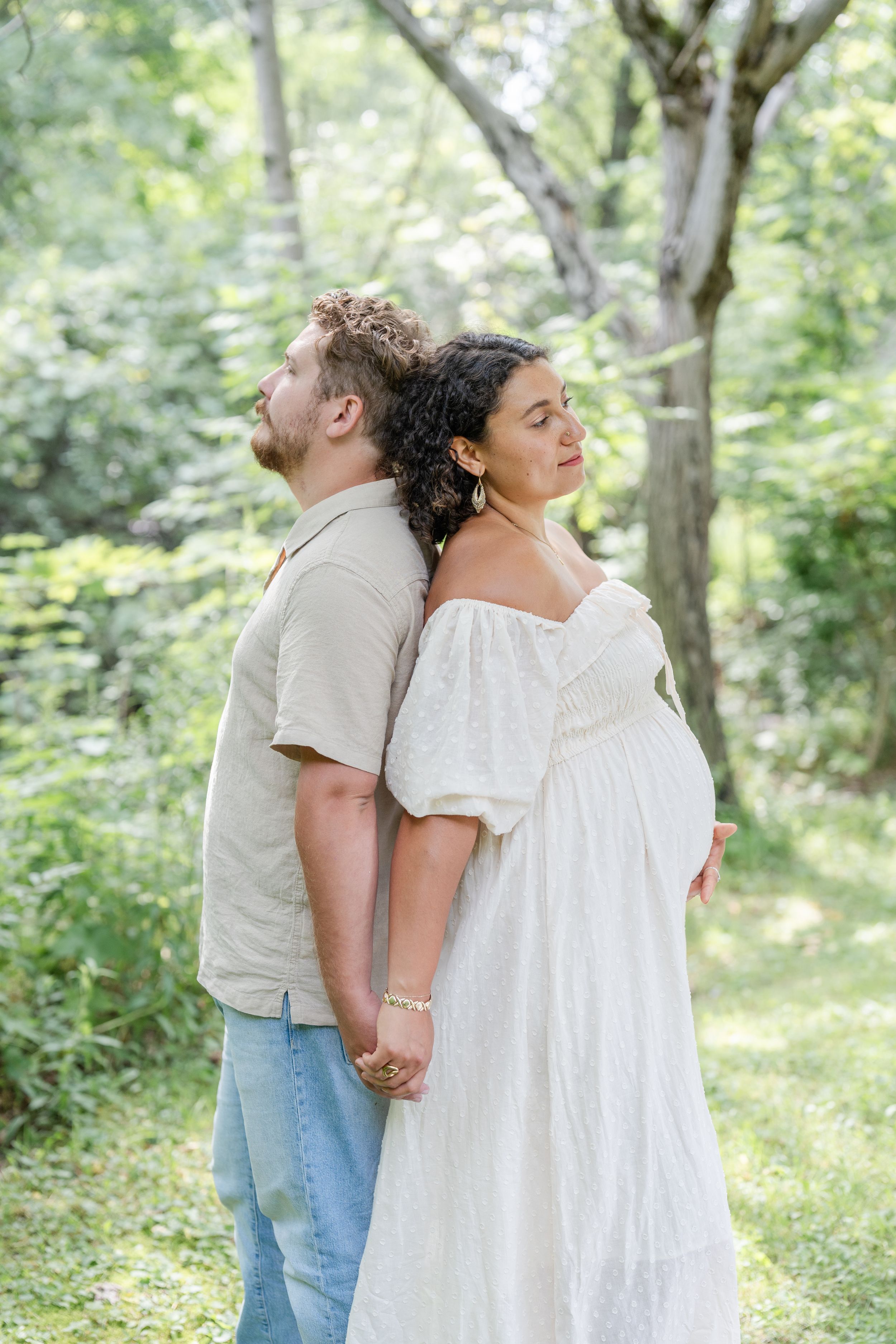 Couple dos à dos lors d'une séance photo de grossesse au bord du fleuve à Saint-Augustin-de-Desmaures par Judith Trudel