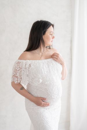 Future maman vêtue de robe en dentelle blanc de la garde-robe cliente du studio de Judith Trudel photographe au coeur de la région de Québec