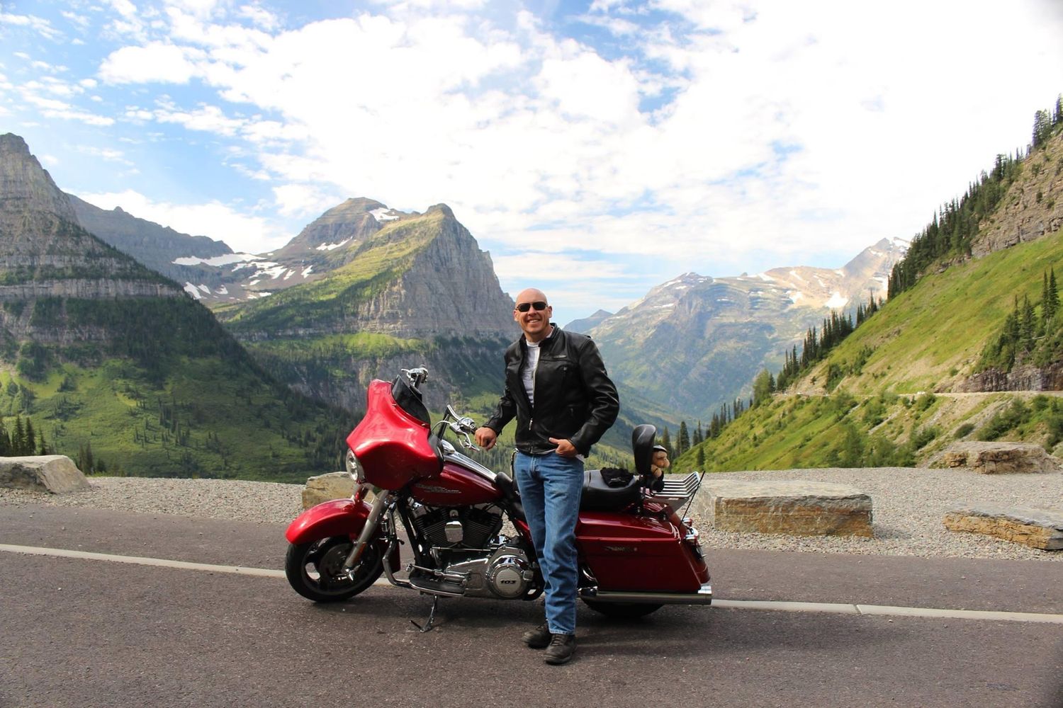 A scenic motorcycle journey through winding mountain roads with dramatic alpine peaks in the background.