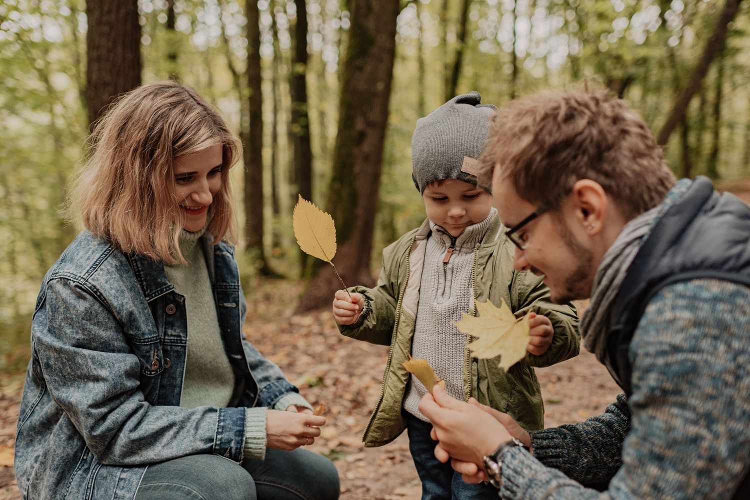 A couple in camouflage jackets shares an intimate moment in a wooded forest setting during autumn.