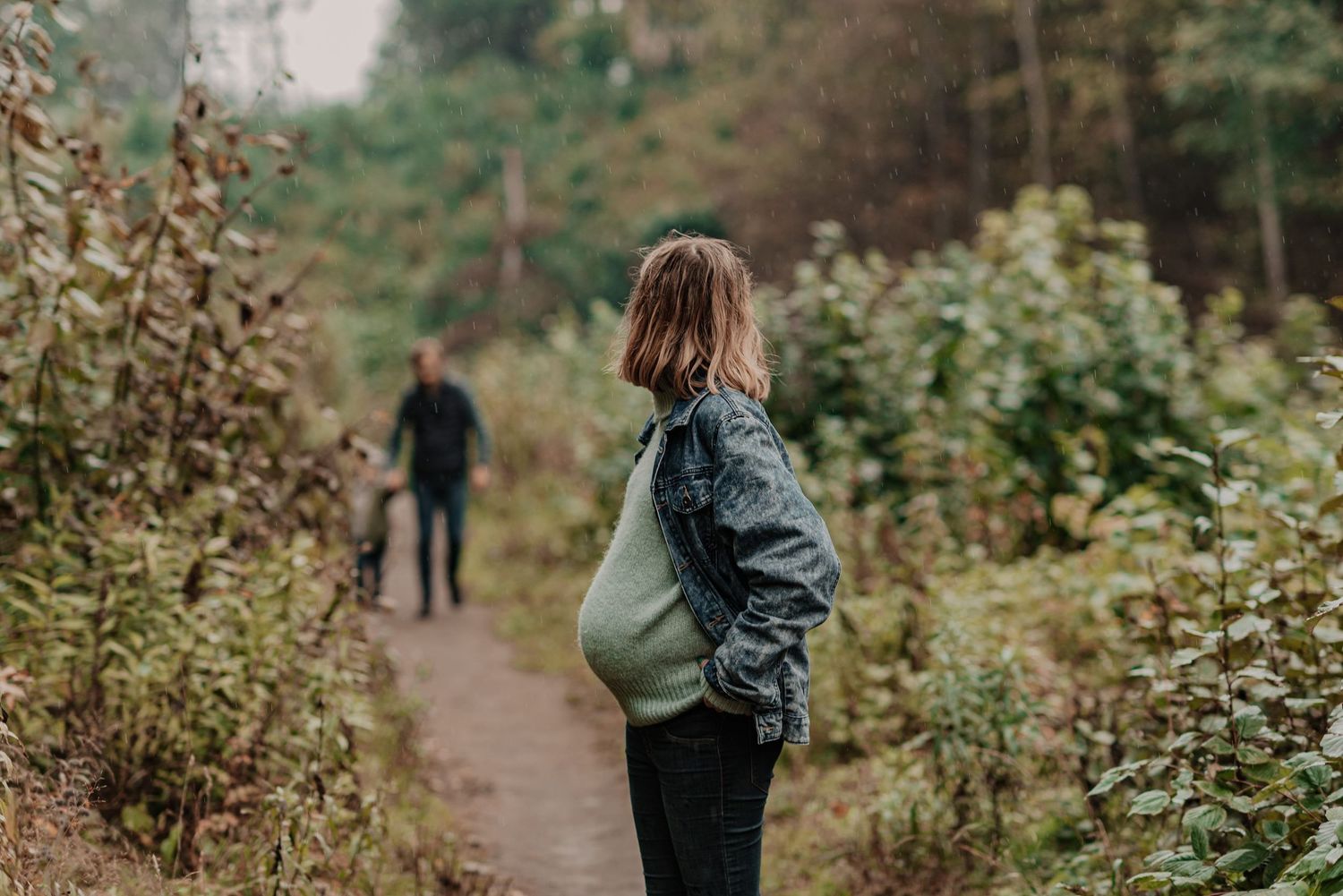 Hikers walking along a scenic forest trail surrounded by lush green vegetation and wildflowers.