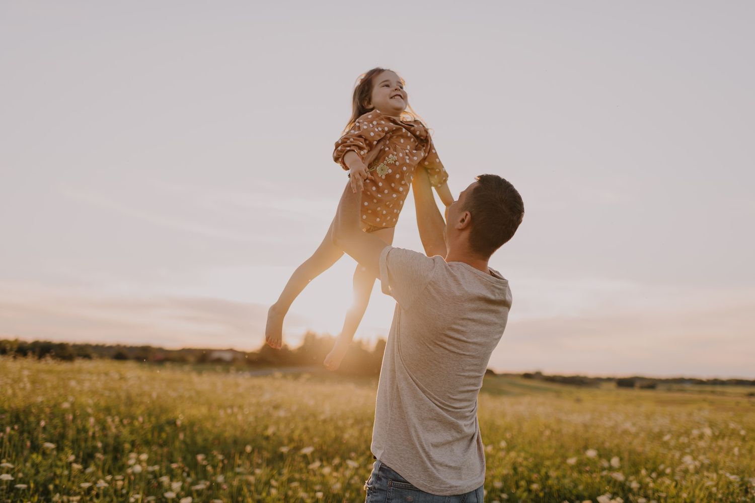 Joyful moment of play captured in a golden summer field at sunset.