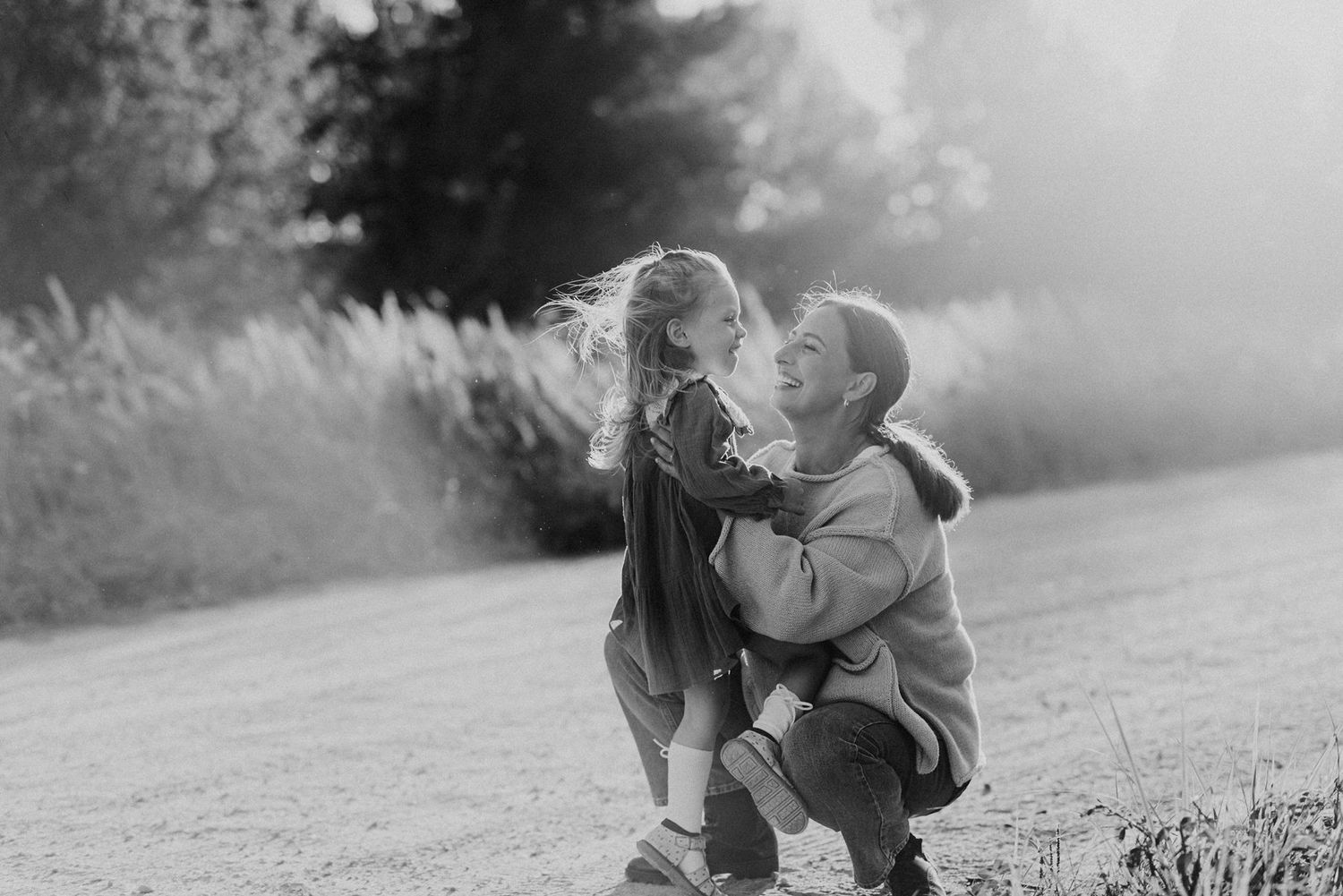 Family plays together in black and white on grassy hillside.