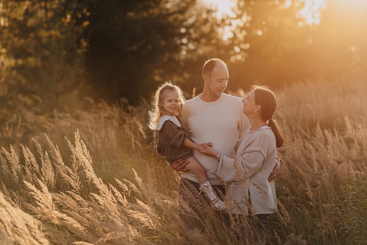Sweet family interactions captured in sunlit field at dusk.
