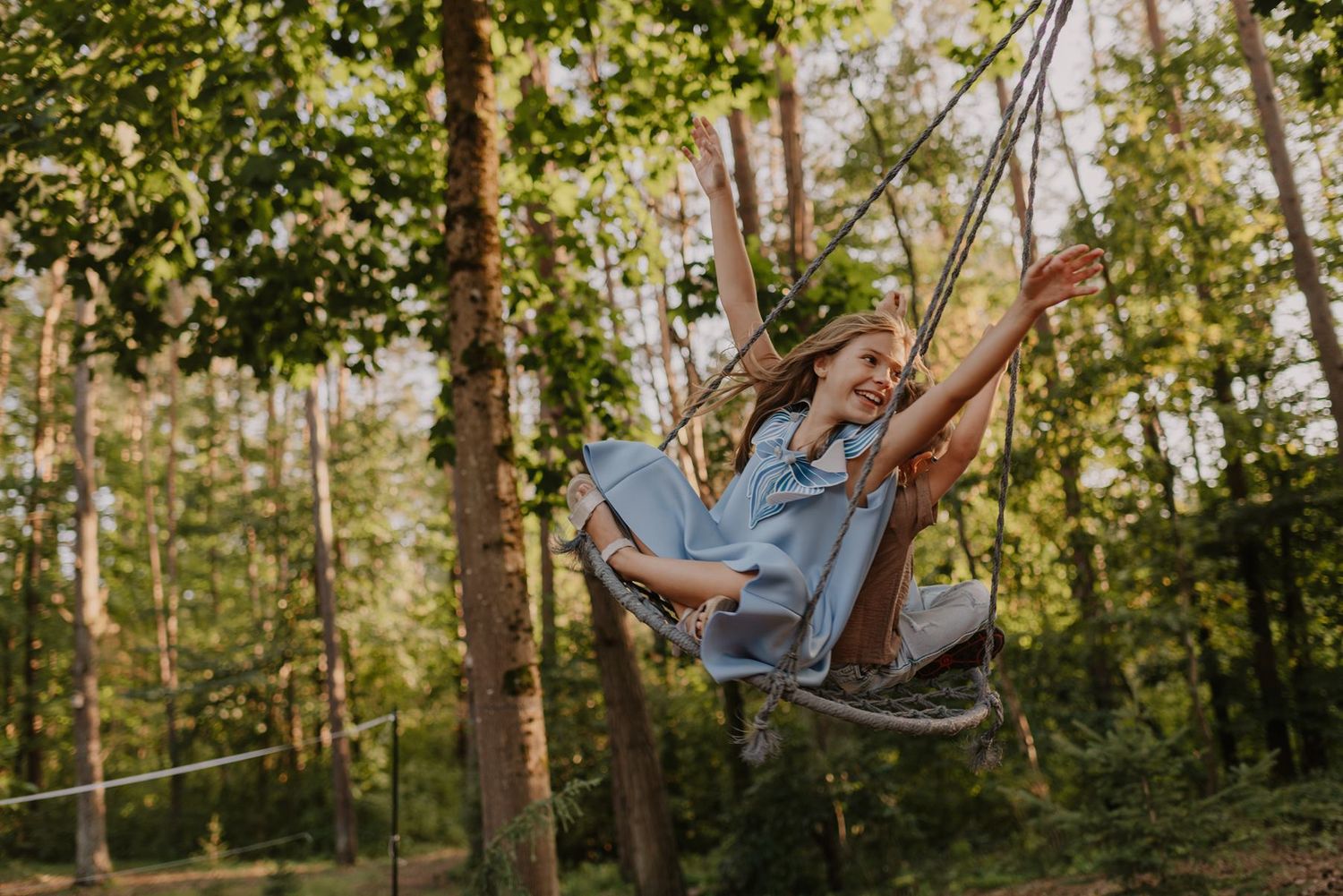 Family enjoying outdoor swings in a lush garden setting at sunset.