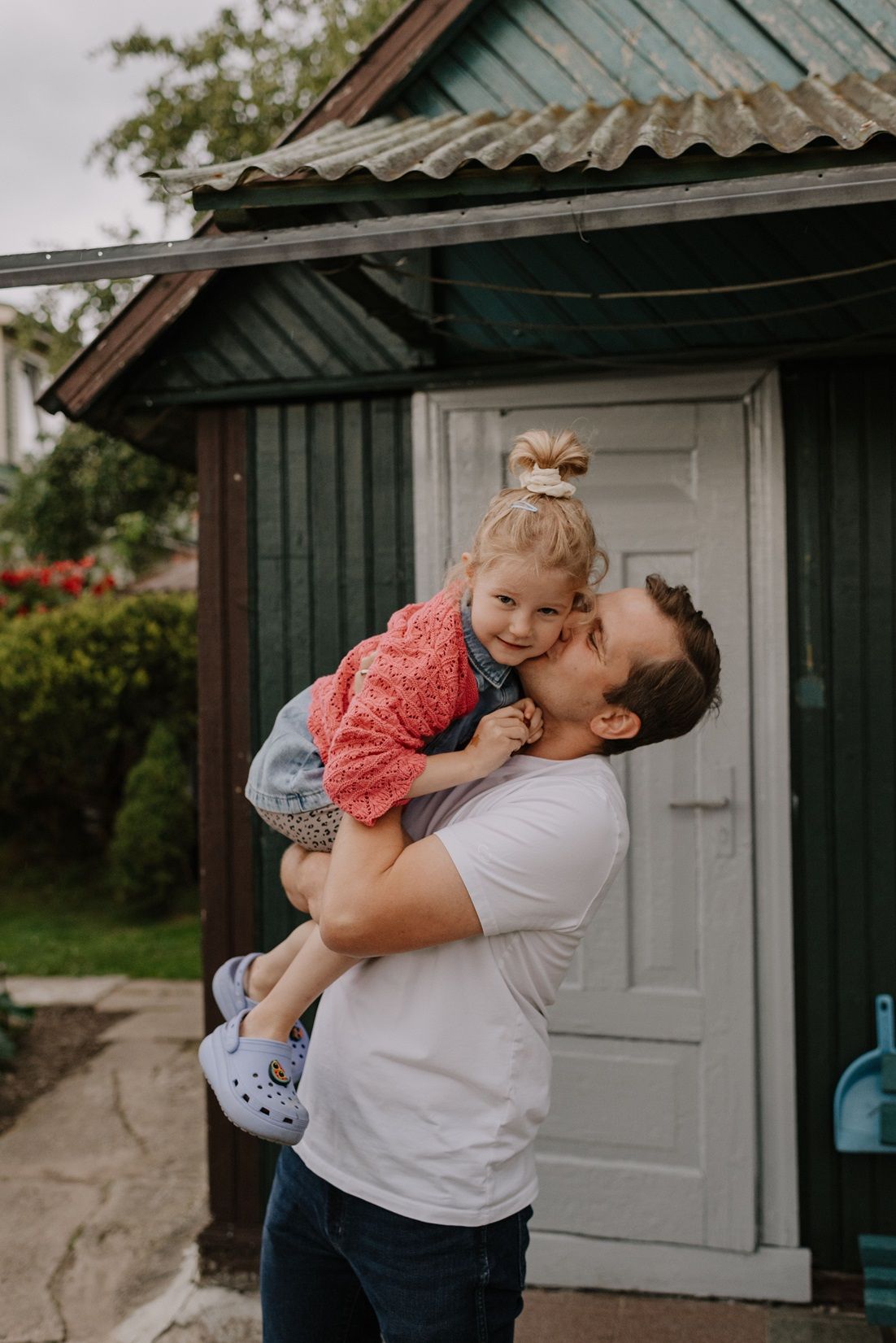 Sweet embrace between siblings in front of a rustic green building.