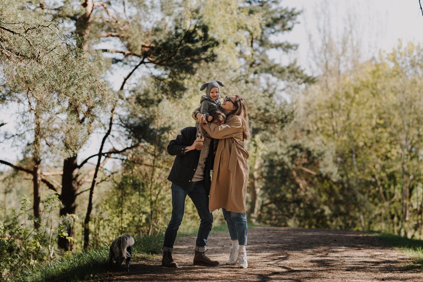 Couple and dog walking together on a scenic autumn forest trail surrounded by golden foliage.
