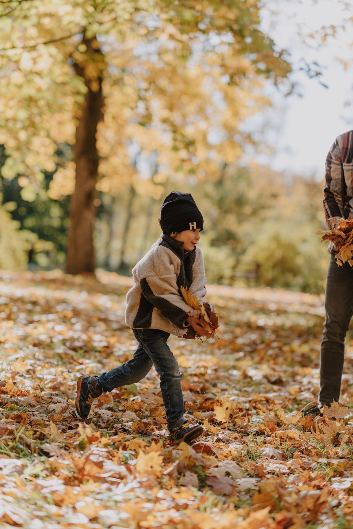 Playing in fallen autumn leaves during a sunny afternoon outdoors.