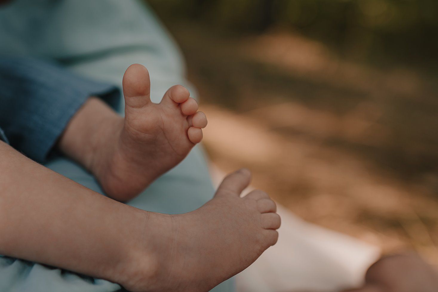 Intimate family moment captured on a cozy blanket outdoors in natural lighting.