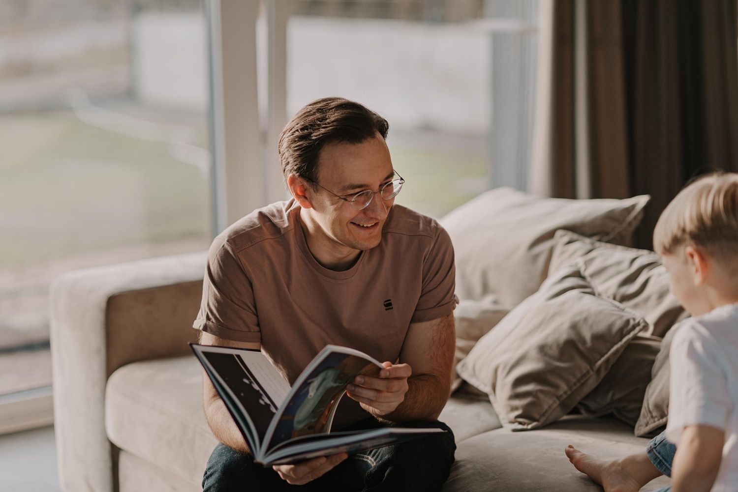 Cozy indoor scene of sharing a book together on a plush sofa.