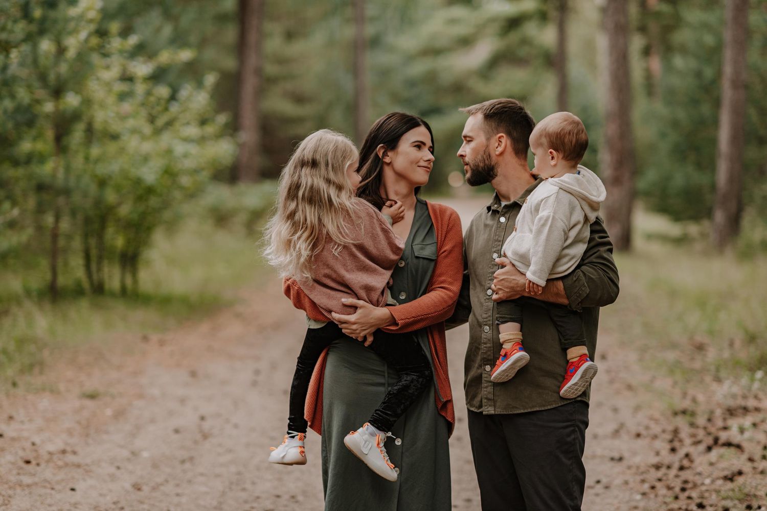 Family sharing tender moments together while walking on a forest trail.