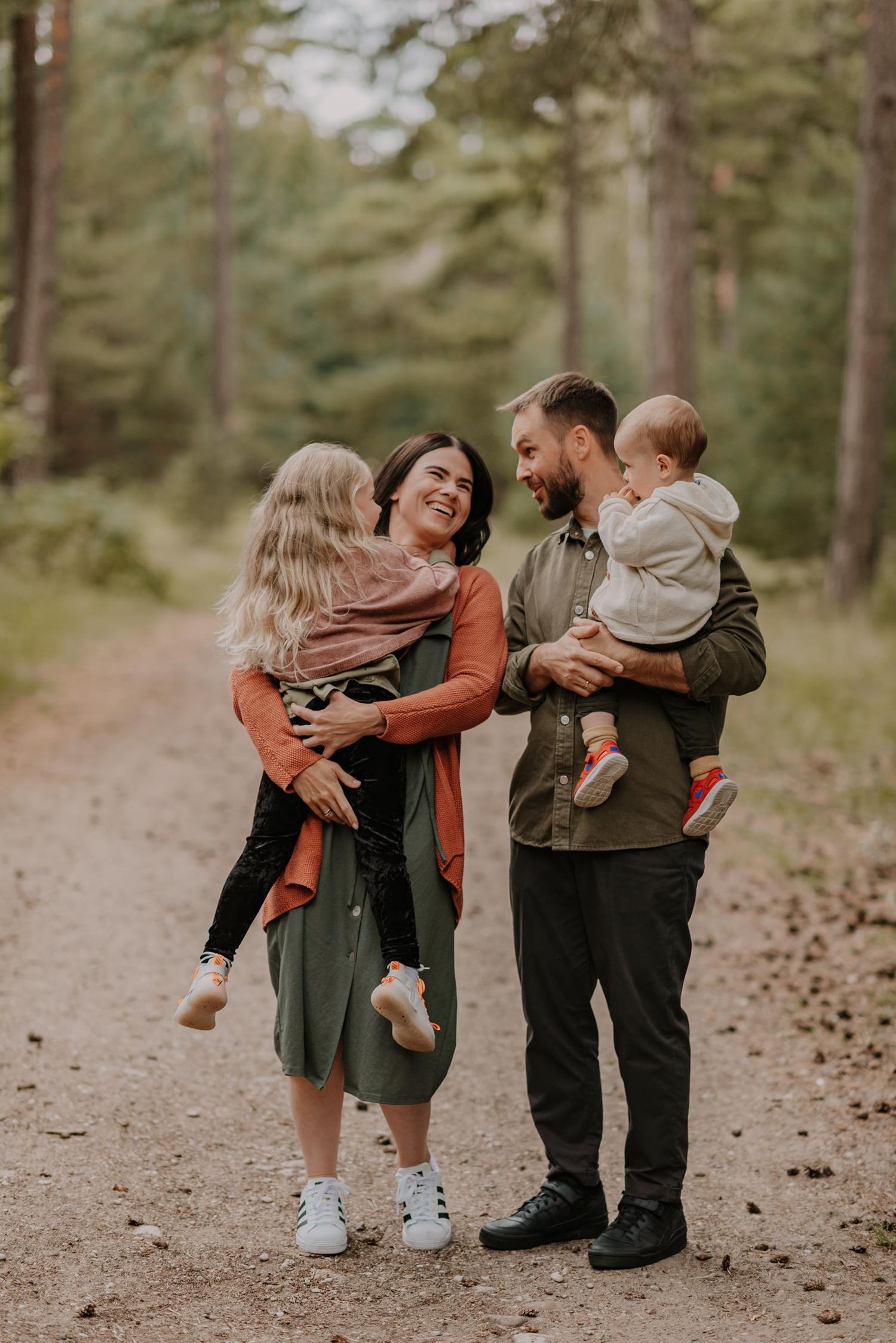 Family sharing laughs while walking together on forest path.