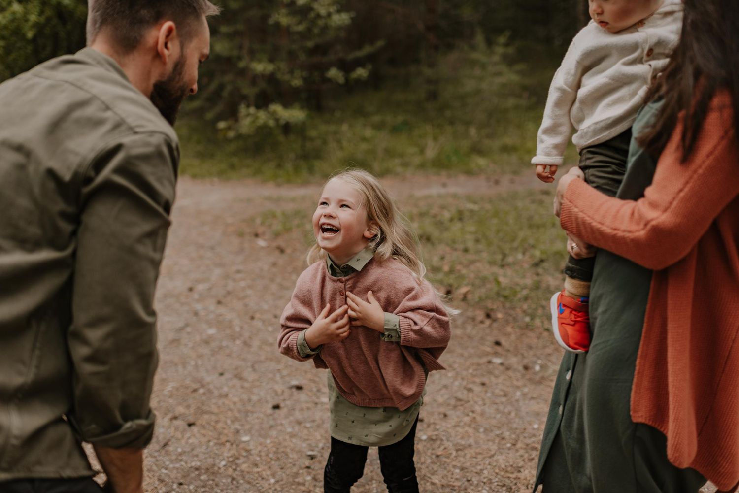 Family plays together outdoors in a candid lifestyle photography session in muted earth tones.