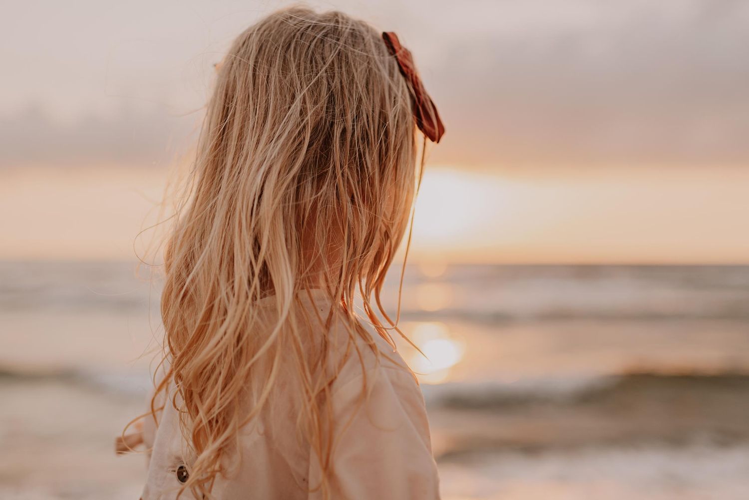 Peaceful beach scene at sunset with soft pink and orange sky.