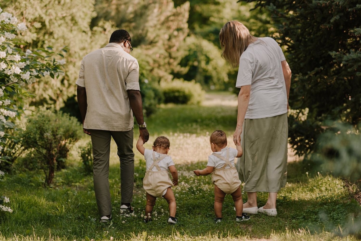 Family walking together on a path through a lush garden landscape.