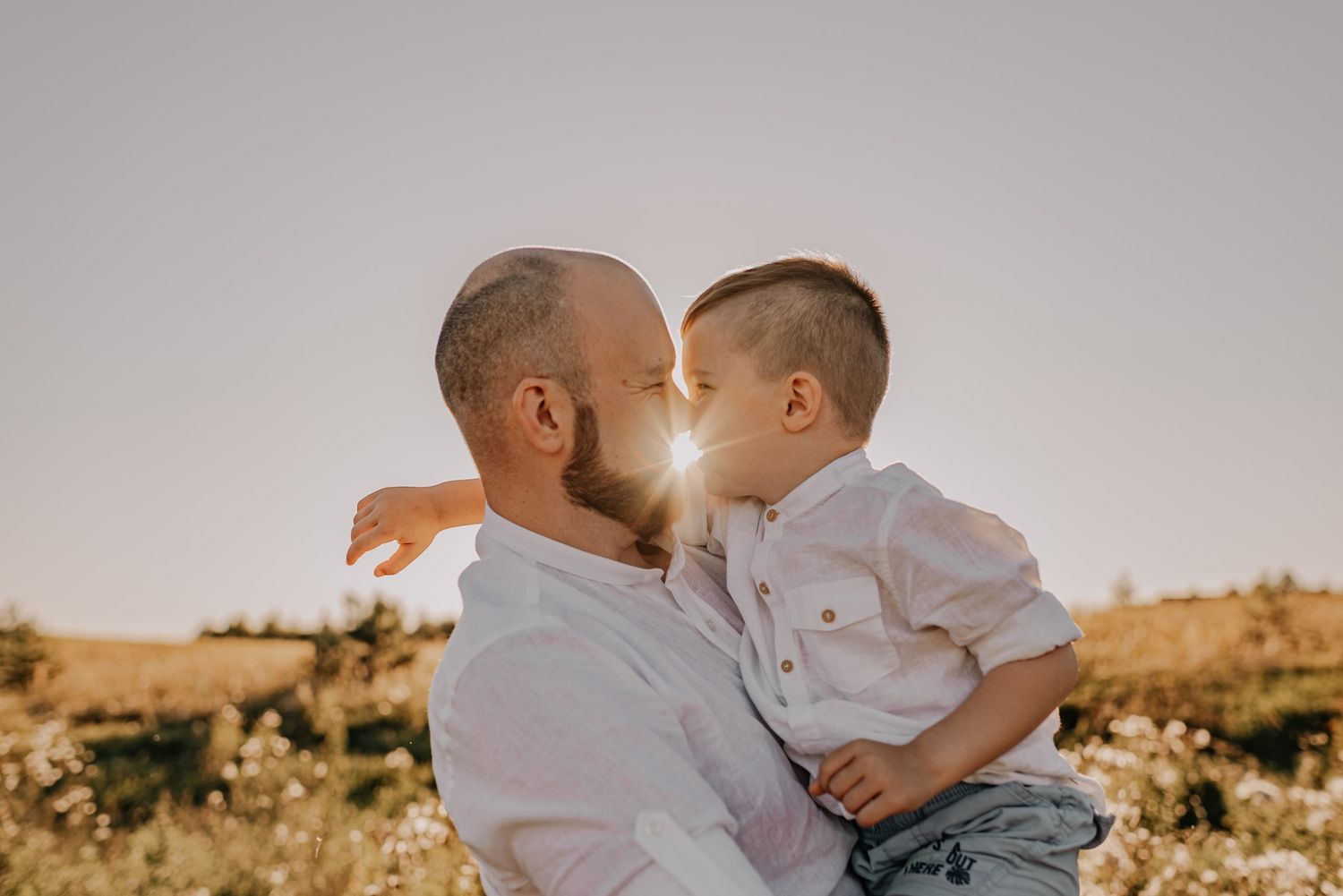 Couple sharing intimate moments together in a field during sunset.