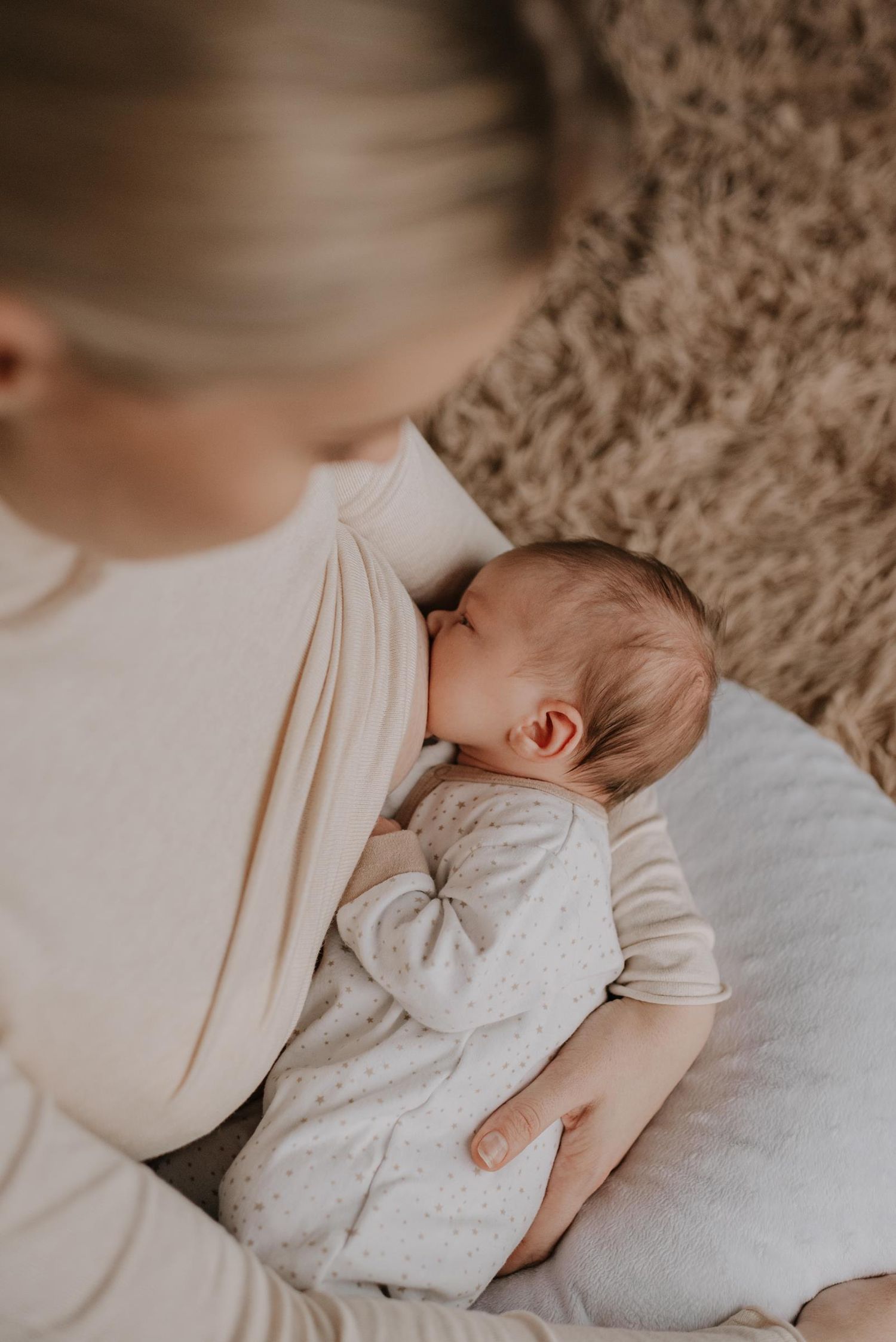 Tender moment between family members with newborn baby in soft indoor lighting.