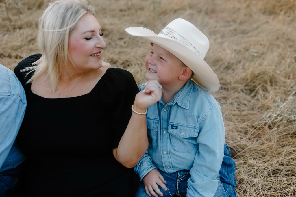 A heartwarming moment captured in a rustic outdoor setting with cowboy hats and casual attire.