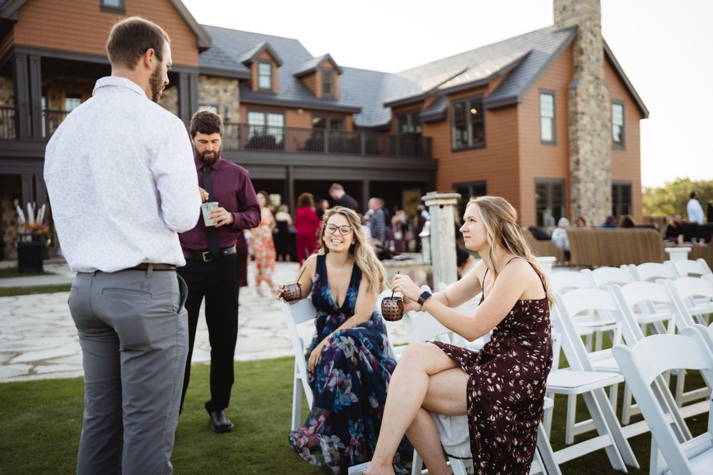 Wedding guests socialize during outdoor cocktail hour at rustic venue.
