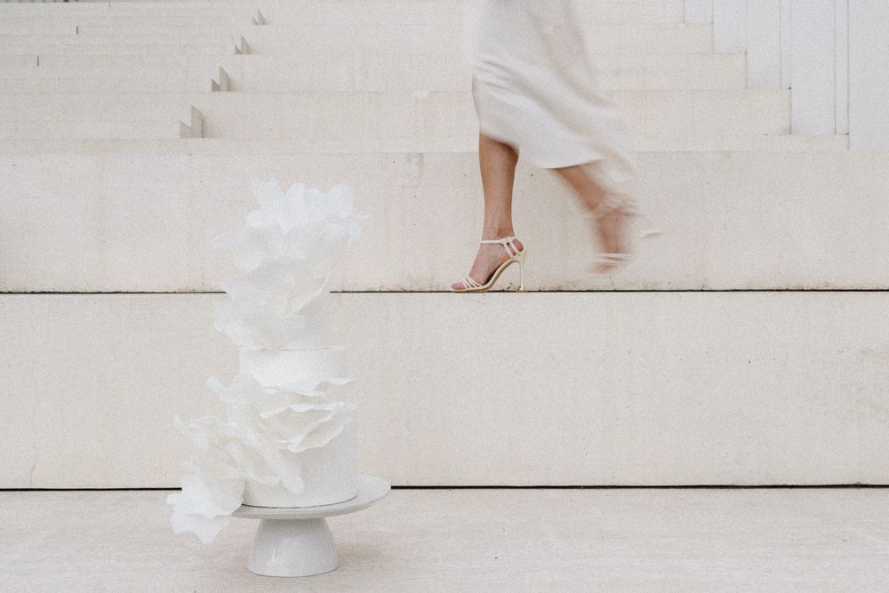 A ballet dancer's feet in pointe shoes next to a white tulle tutu on wooden floorboards.