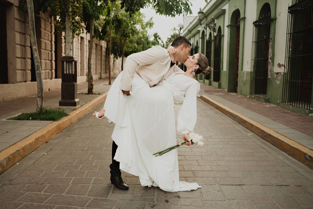 Romantic pose, groom lifting bride for a kiss in the street