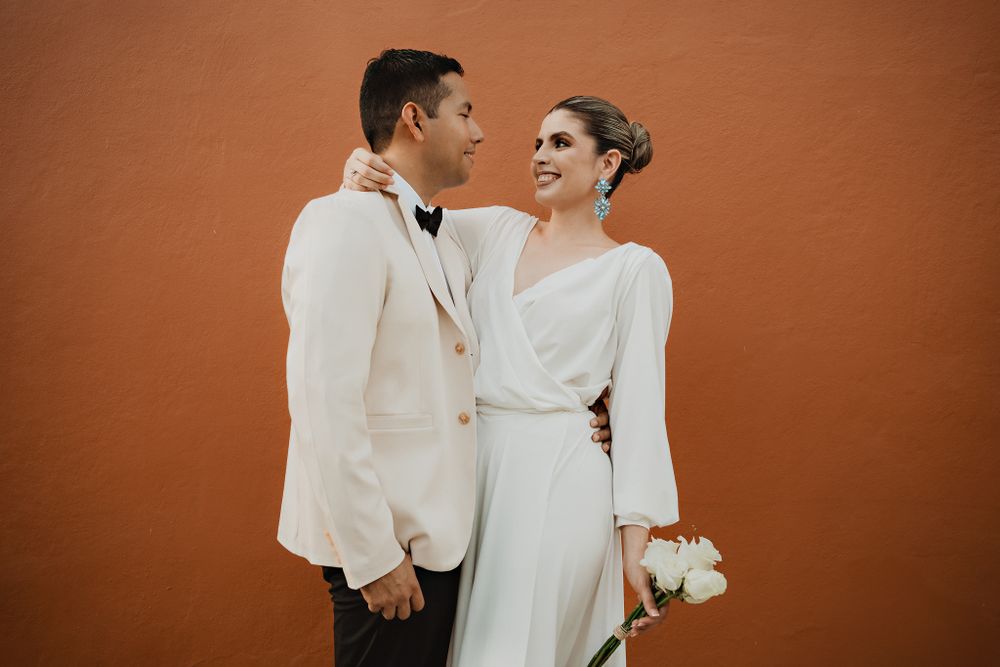 Couple embracing, gazing at each other with a flower, colorful wall background