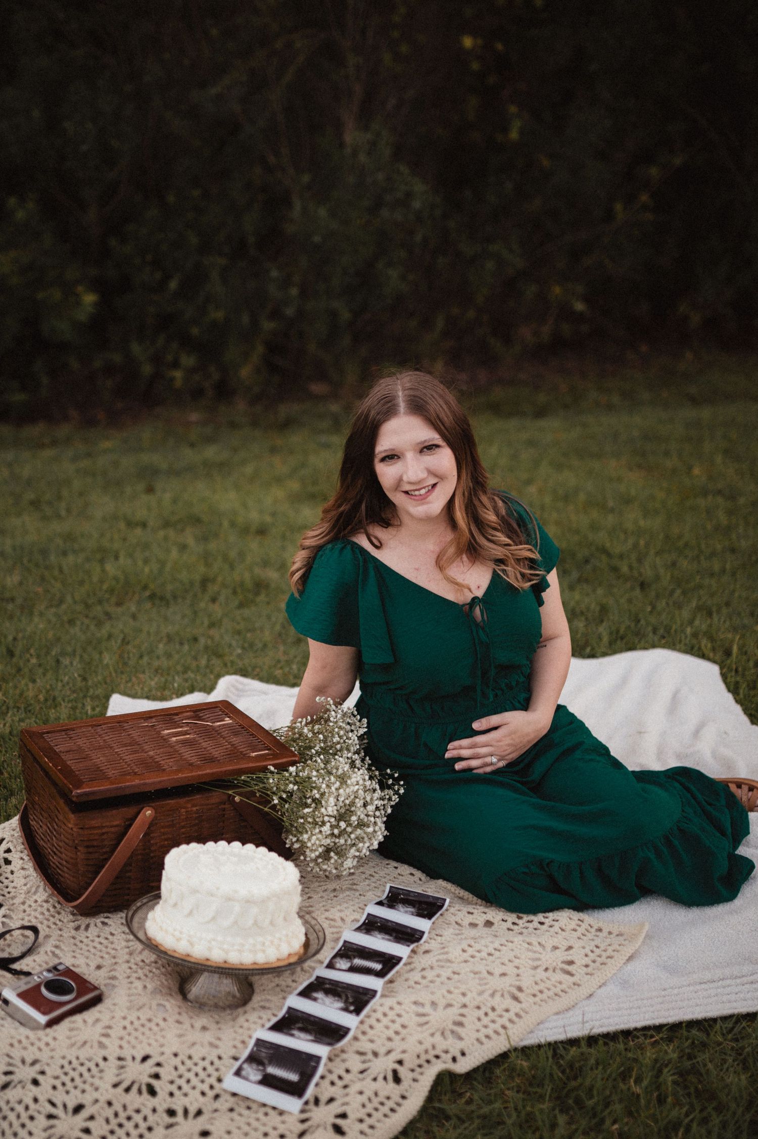 A vintage-inspired picnic scene with books, baby's breath flowers, and a lace blanket on grass with someone in emerald green.