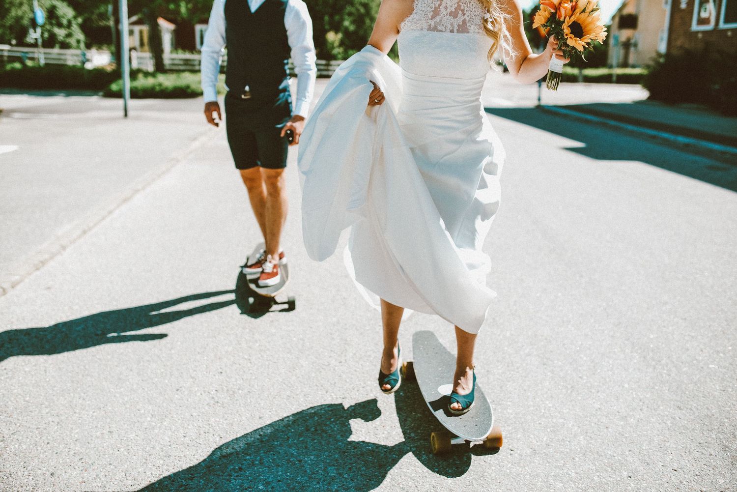Playful wedding photo showing dress and shoes while walking on sunny street.