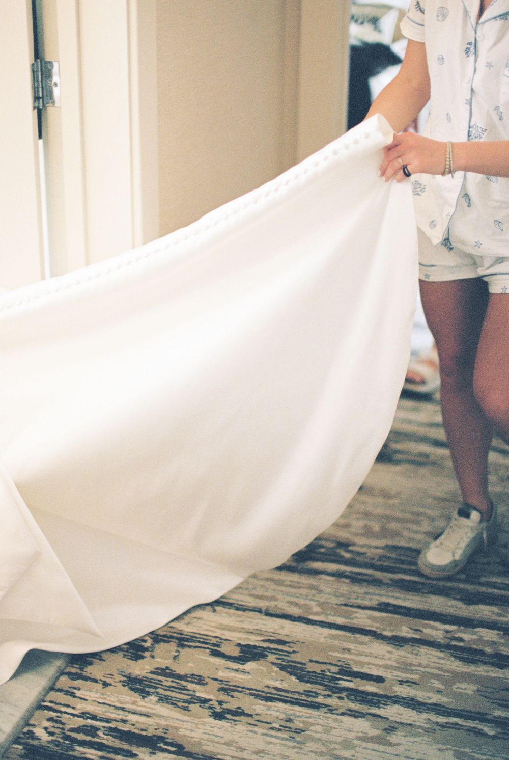 A flowing white wedding dress train trails across distressed wooden flooring.