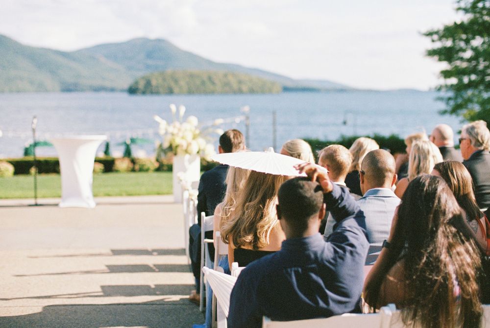 An outdoor wedding ceremony setup overlooking a scenic mountain lake with white floral arrangements and chairs.