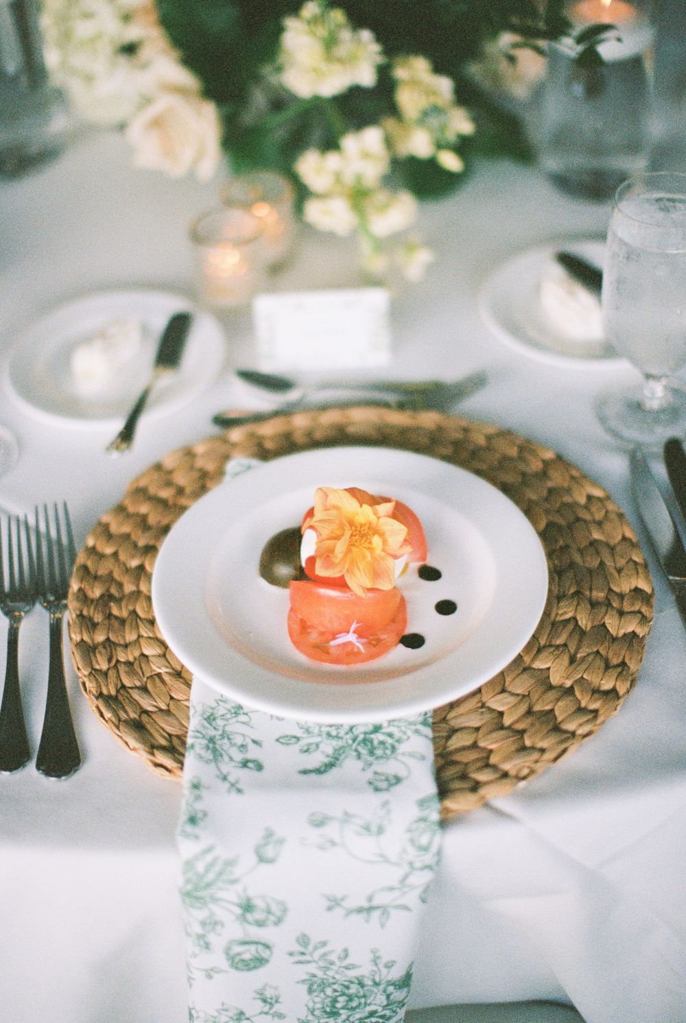 Elegant table settings with coral flowers on white plates and gold charger plates create a sophisticated wedding reception look.