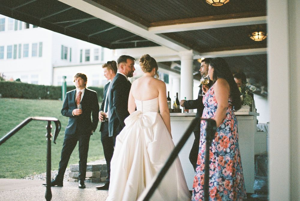 Wedding party members gather on a covered outdoor walkway at a venue.