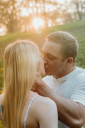 An intimate kiss between a couple captured during golden hour in nature.