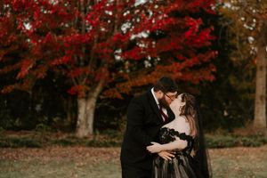Couple sharing an intimate moment under red fall foliage during their wedding photoshoot.