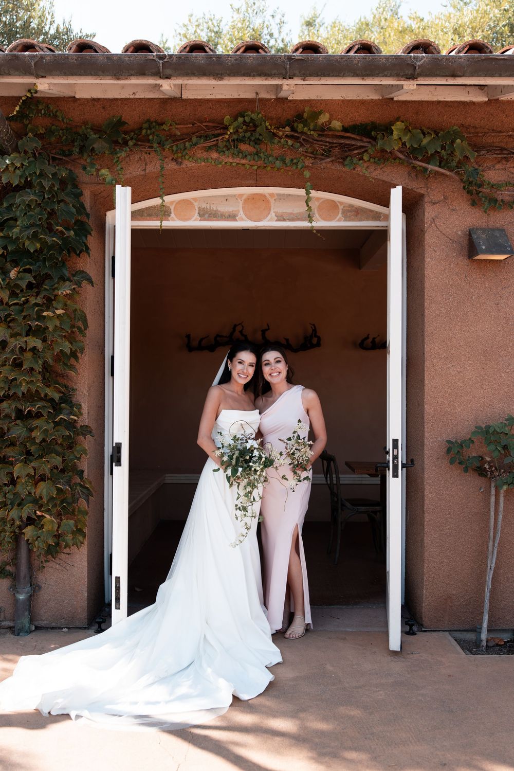 A series of wedding photos showing two people in white dresses posing together in a rustic adobe courtyard.